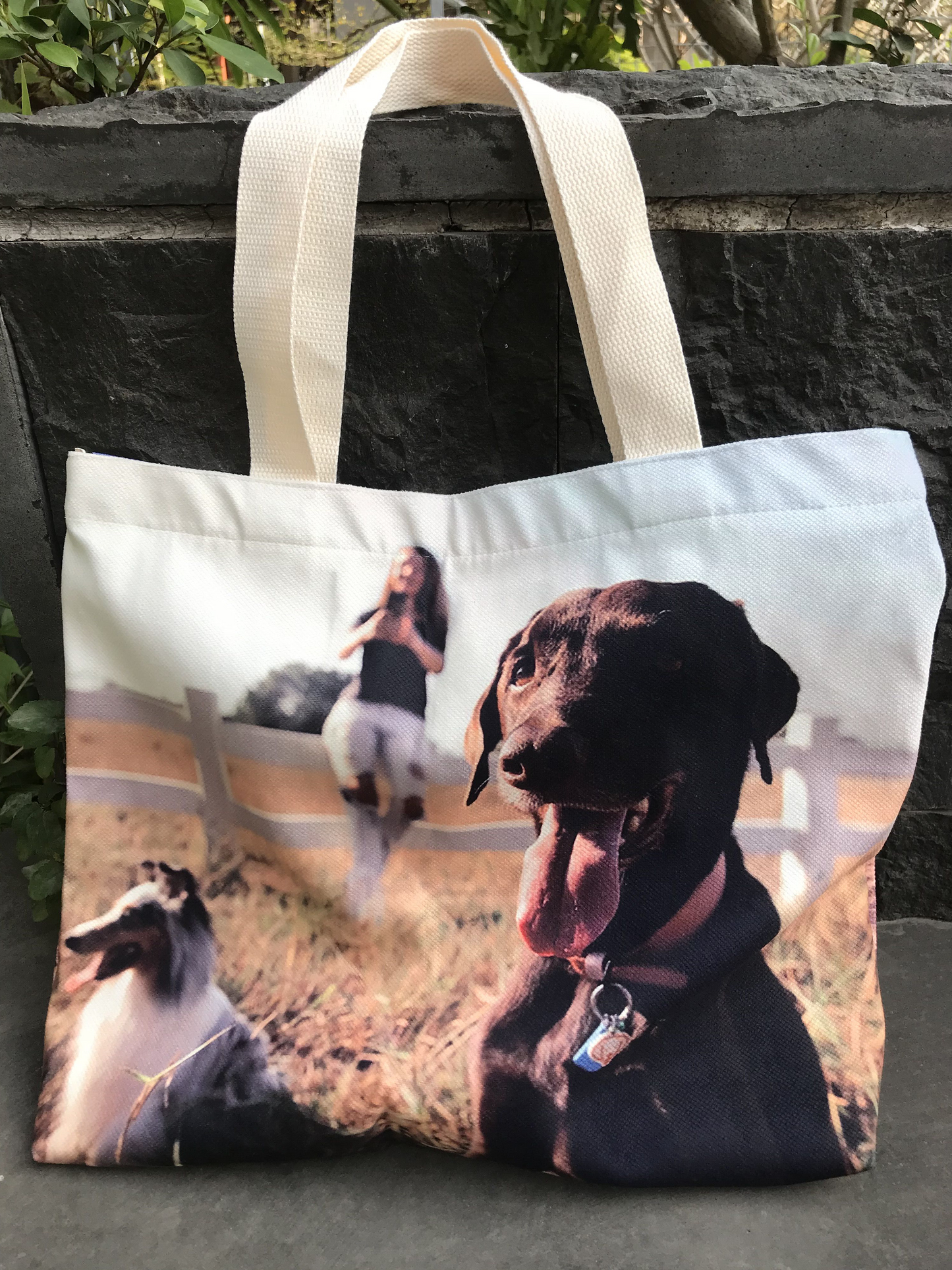 A all over print custom tote bag with a photo of a woman and two dogs is a thoughtful and unique gift. The bag is large and the photo is vibrant, making it a conversation starter.
