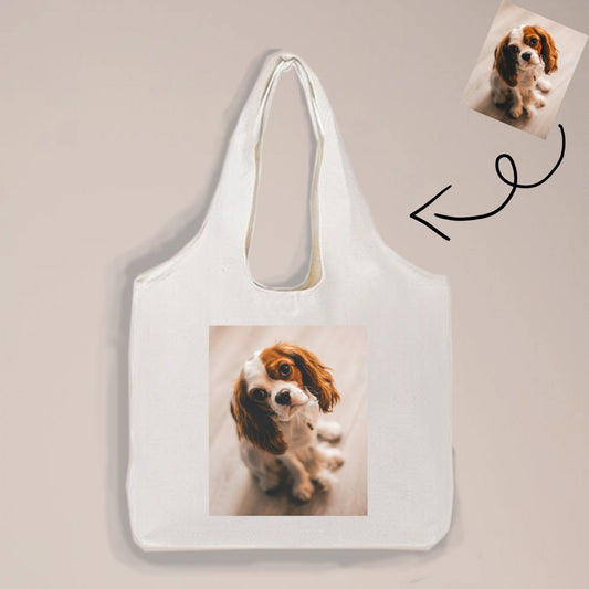 A simple but elegant tote bag that is printed with a picture of a Cavalier King Charles Spaniel dog is made of canvas.