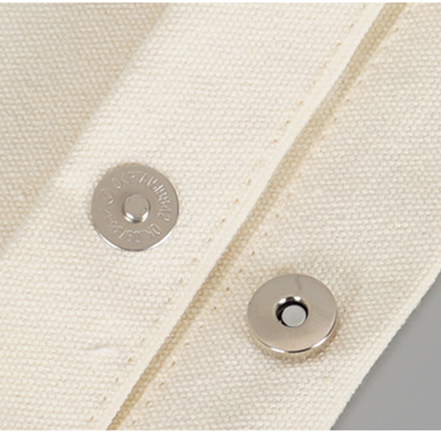 A close-up of a high quality button on a piece of fabric of a plain personalized crossbody and tote bag. 