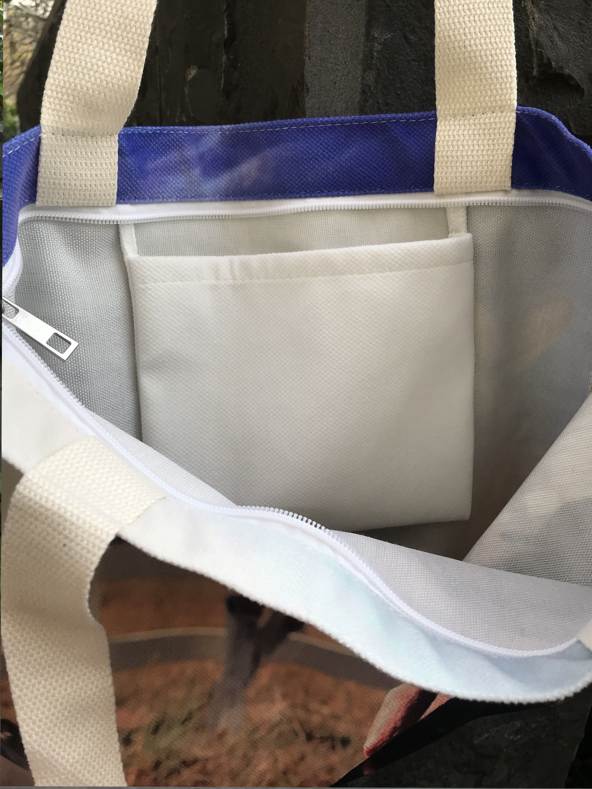 A zippered tote bag with an all white interior and an inner pocket.