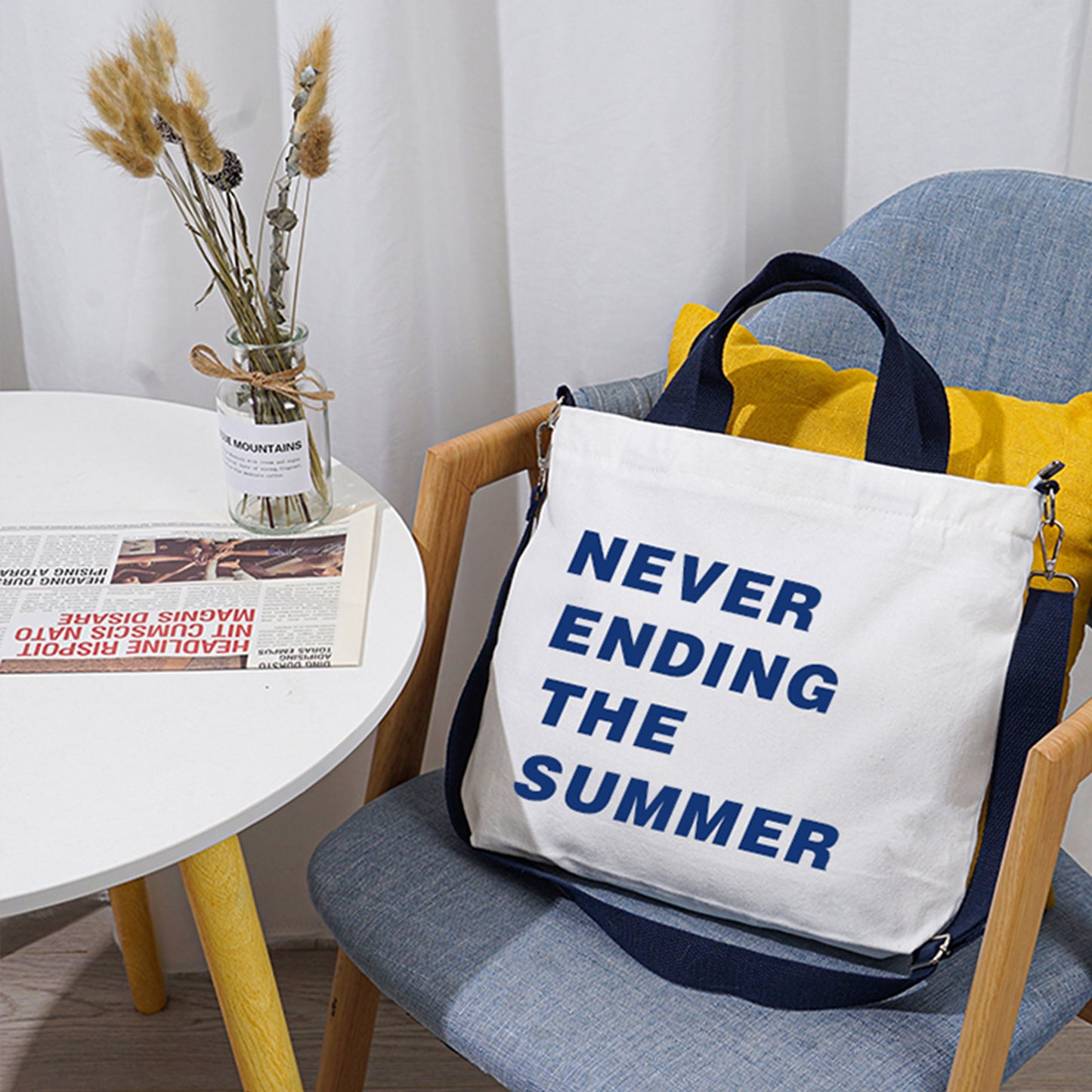 A long strap crossbody bag with texts printed on it. The bag is white and its strap is blue. 