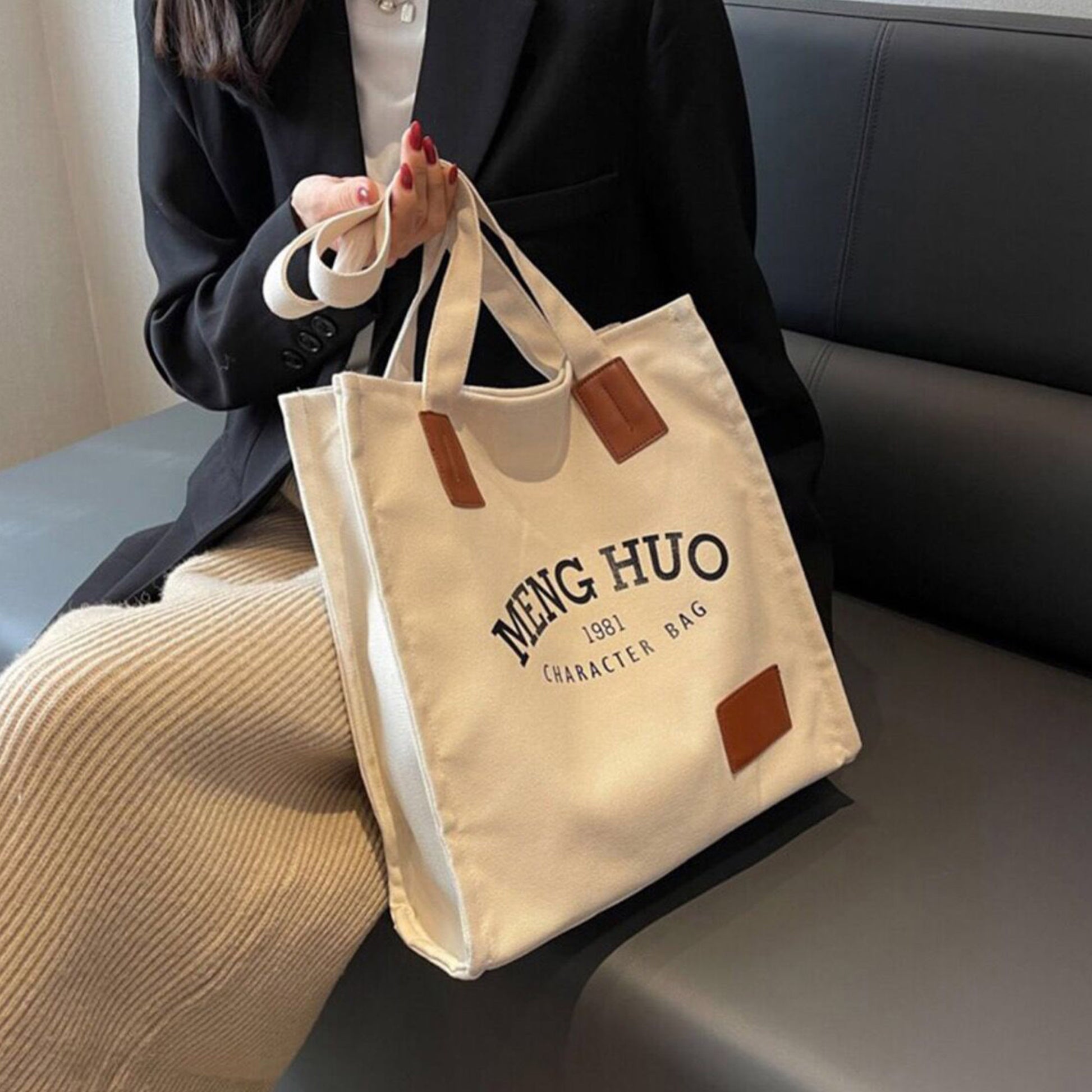 A girl is carrying a quality thick personalized tote bag on her hand sitting on the chair. The tote bag is printed with some words.