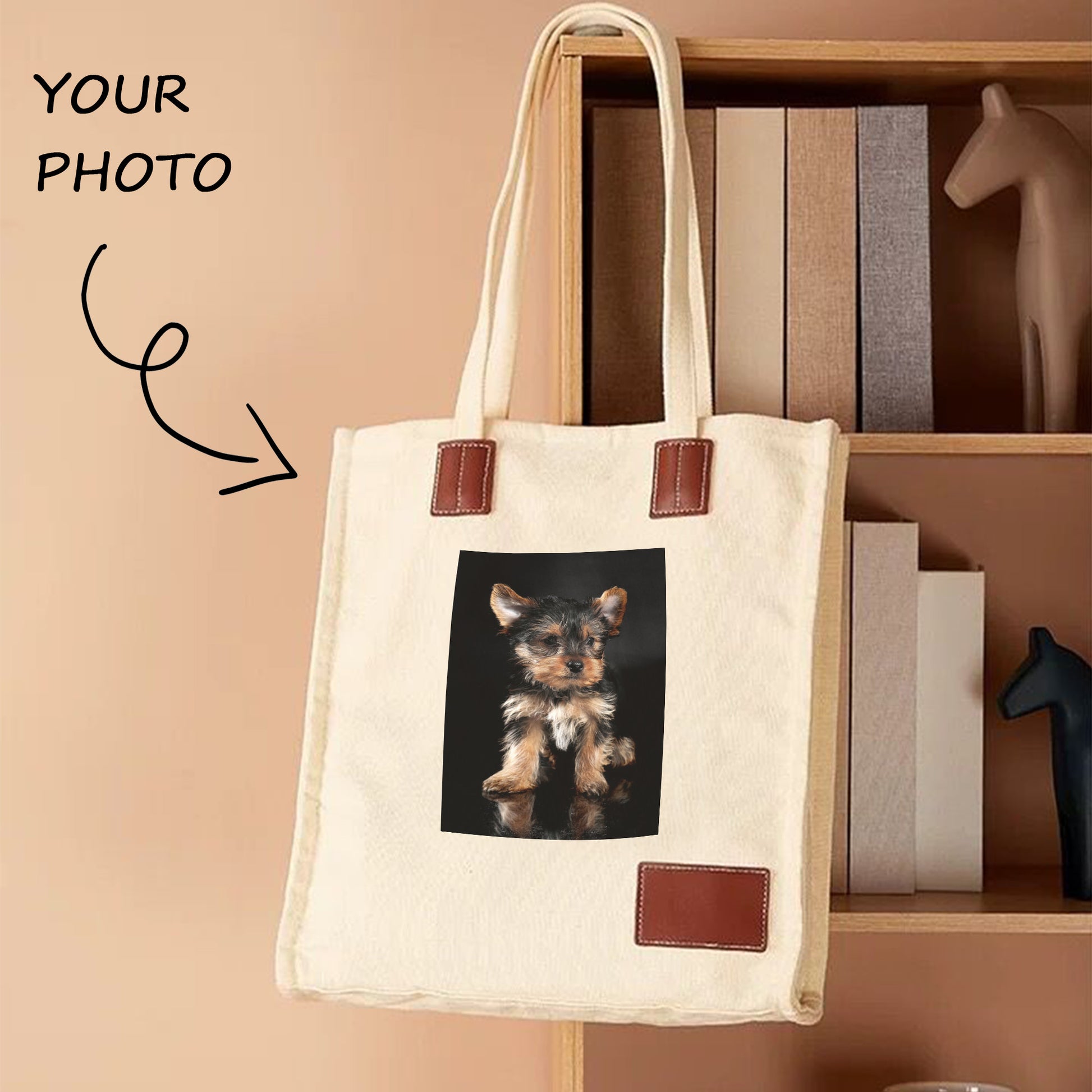 A white custom photo tote bag with an image of a dog on it hangs on the bookshelf. The tote bag is thick and in good shape.