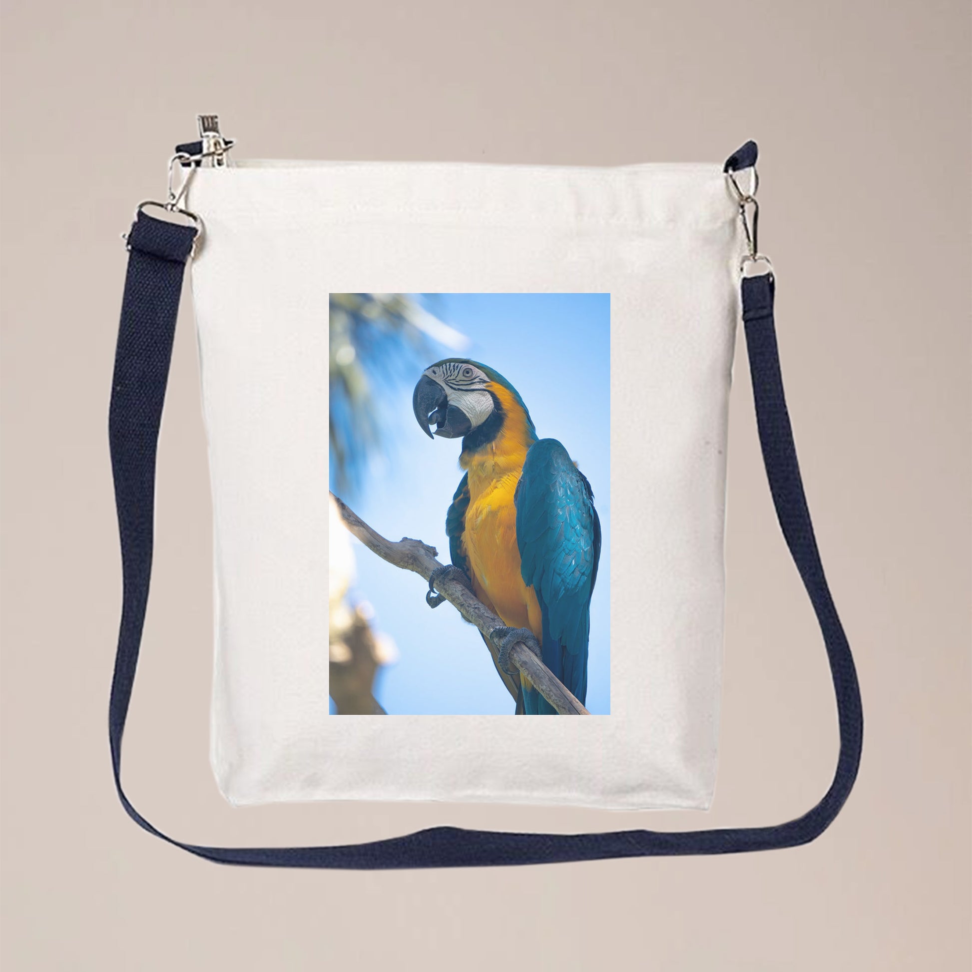 A photo of a bird is printed on a white canvas bag with a blue strap. The bag can be used as the crossbody bag because it has a long strap which is adjustable. People can personalize this crossbody bag with pet photos, initials, logos, text, etc.