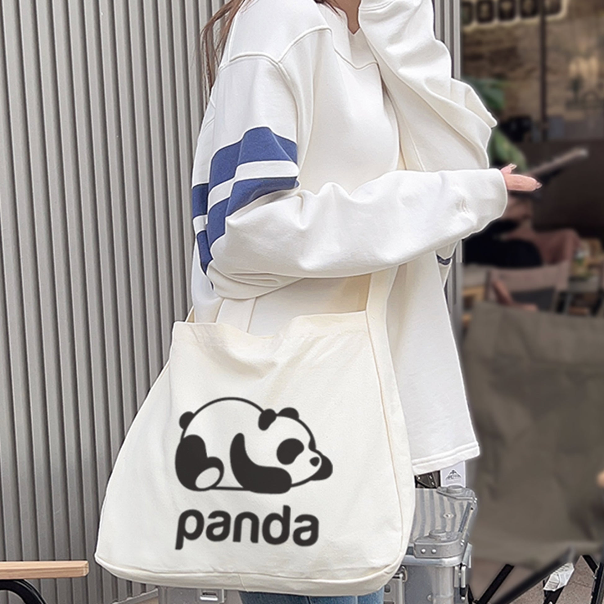 A person in blue jeans and white sneakers is wearing a personalized white crossbody bag with a cute panda printed on it.