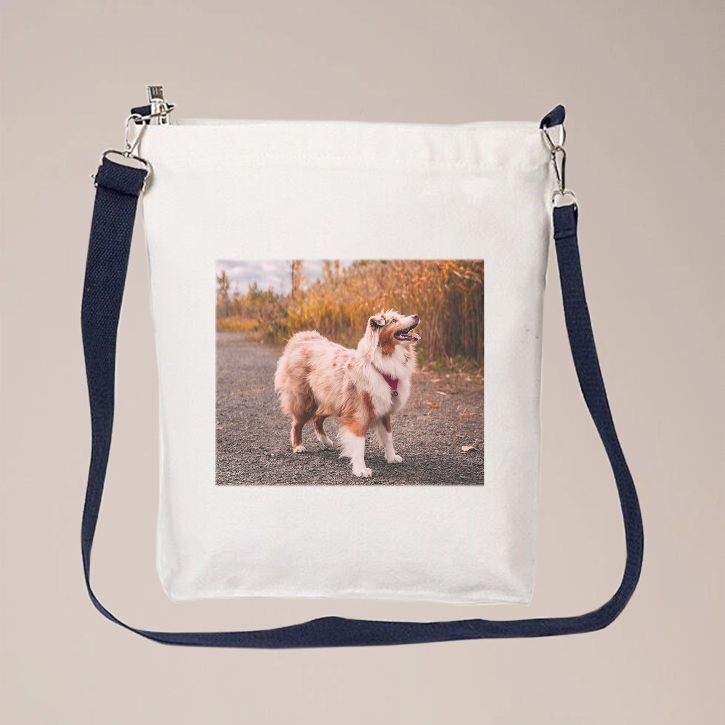 A photo of a dog is printed on a white crossbody bag with a long, blue, adjustable strap. People can personalize this crossbody bag with their own photos, pet photos, initials, logos, text, etc.